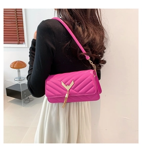 Detail of fuchsia quilted handbag with gold V-shape buckle and elegant metal tassel