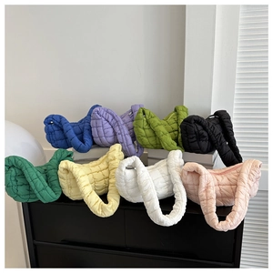 Collection of quilted puffer shoulder bags in eight vibrant colors on minimalist display