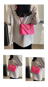 Detail of fuchsia stone-embossed crossbody bag with chunky gold chain and leather strap