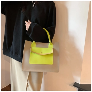 Detail of grey leather tote bag featuring vibrant neon green pocket and gold hardware accent