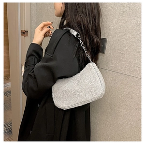 Détail du sac sous le bras en laine d'agneau blanche avec chaîne argentée sur manteau