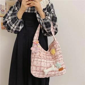 Detail der rosa-weißen Tweed-Tasche mit flauschigen Sternen und Blumenanhängern