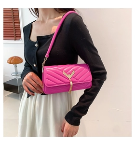 Detail of rose pink crossbody bag featuring V-shaped quilting and gold tassel charm