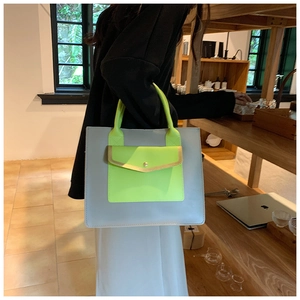 Detail of grey tote bag with neon green pocket and golden snap button detail