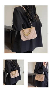 Detail of beige crocodile pattern flap bag with gold chain strap on black blazer