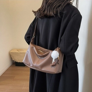 Brown litchi grain leather shoulder bag featuring a white faux fur pompom charm detail