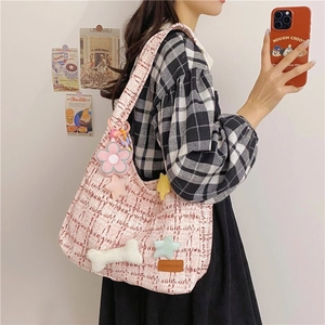Detail der rosa-weißen Tweed-Schultertasche mit süßen Plüsch-Anhängern und Lederpatch