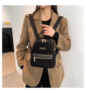 Détail du mini sac à dos noir avec fermetures éclair dorées et écusson FASHION