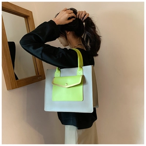 Detail view of large grey tote bag with neon green handles in a minimalist indoor setting