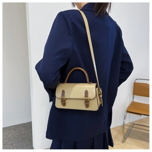 Detailed view of vintage crossbody bag with contrast stitching on a model's shoulder