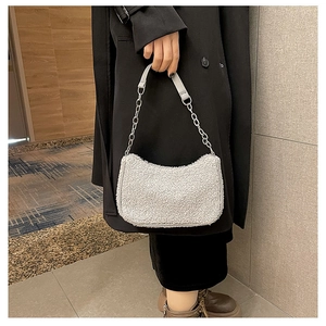 Détail de la texture douce en laine d'agneau et de la chaîne en métal sur le petit sac