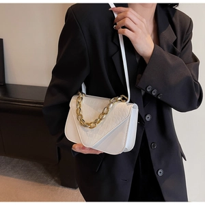 Detailed view of white crocodile embossed square bag with bold gold chain link handle