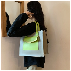 Detail of grey-blue tote bag with lime green pocket showing stitching and metal button