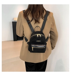 Gros plan d'un mini sac à dos en daim noir avec fermetures éclair dorées sur modèle
