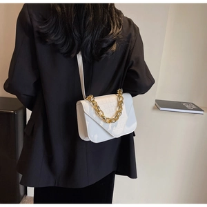 Detail view of white crocodile embossed leather square bag with gold chain strap accessory