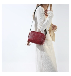 Detail of vintage red crossbody bag with tassel charm and wide woven jacquard strap