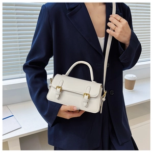 Close-up of a white vintage small square crossbody bag with gold buckle details