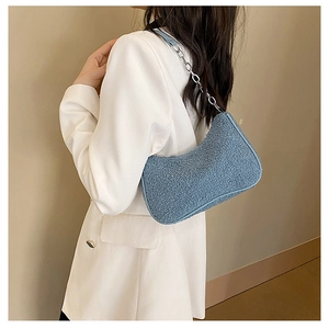Gros plan du sac bandoulière en polaire bleu clair avec chaîne sur un blazer blanc