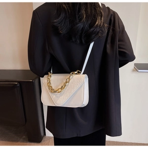 White faux crocodile skin square bag with gold chain strap shown on a model's shoulder
