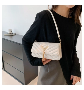 Detail of white quilted handbag with golden metal Y-pendant and stylish fringe tassel