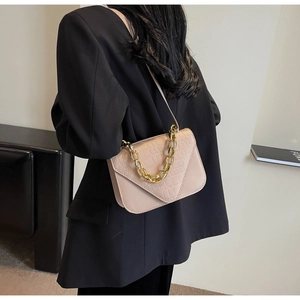 Detail of minimalist stone pattern square bag with chunky gold chain and leather strap
