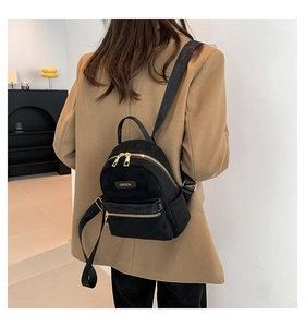 Mini sac à dos noir moderne avec fermetures éclair dorées porté sur un blazer camel