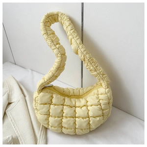 Detail of light yellow quilted puffy shoulder bag with ruched handle and cloud-like texture