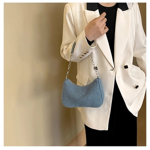 Détail d'un sac croissant en polaire bleue porté par un mannequin avec chaîne argent