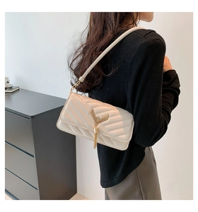 Detail of cream quilted shoulder bag with elegant tassel V-shaped metal hardware accessory