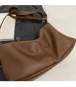 Detail of dark brown lychee textured leather tote bag with golden metal hardware buckle