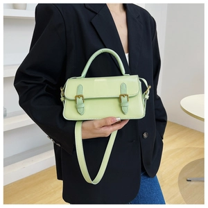 Detail of mint green square handbag with gold buckles and premium leather texture