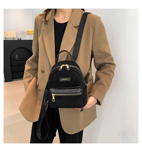 Détail du mini sac à dos noir avec emblème de mode, fermetures dorées et texture en suédine