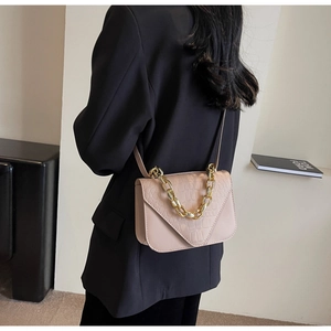 Pink croc-embossed small square bag with gold chain handle on model's shoulder