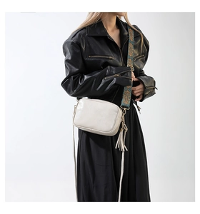 Detail of off-white crossbody bag with bohemian embroidered wide strap and leather tassel