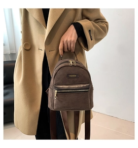 Gros plan d'un mini sac à dos en daim marron foncé avec fermetures éclair dorées