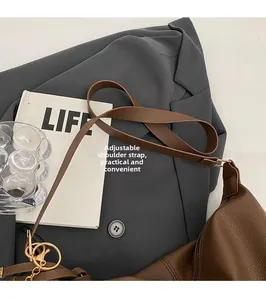 Detail of brown lychee grain leather crescent bag with adjustable golden hardware strap