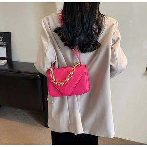 Detail of flamingo pink crossbody bag with crocodile texture and gold chain strap
