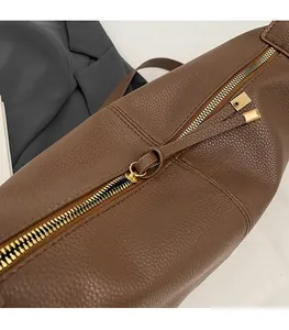 Macro detail of dark brown leather texture and smooth golden metal zipper on tote bag