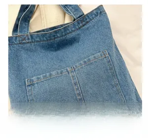 Detailed close-up of dark blue denim tote bag with textured fabric and brown stitching