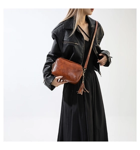 Brown vintage camera bag with matching tassel charm and wide shoulder strap on model