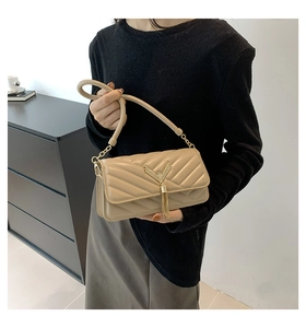 Close-up of beige quilted crossbody bag featuring V-shaped hardware and elegant tassel detail