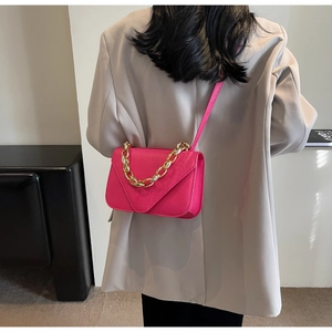 Detail of fuchsia crocodile pattern leather bag with gold chain and V-flap design