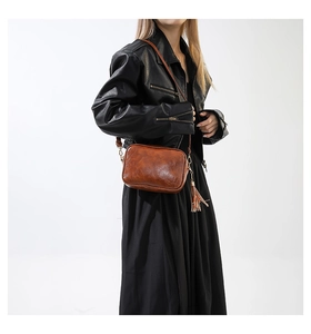 Close-up of vintage brown leather crossbody bag with fringe tassel and golden hardware