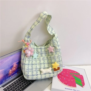 Nahaufnahme mintgrüne Cord-Schultertasche mit Karomuster und süßen Plüsch-Anhängern im Detail