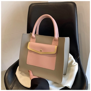 Detail of grey and pink tote bag featuring a front envelope pocket and gold accents