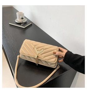 Detail of beige quilted leather bag with elegant golden V-shaped tassel and hardware