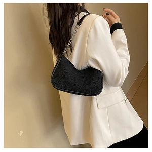 Vue détaillée du sac baguette en molleton noir avec chaîne argentée sur blazer blanc