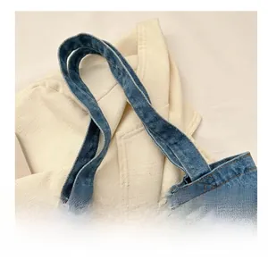 Close-up of blue denim handbag featuring contrast stitching and reinforced handles