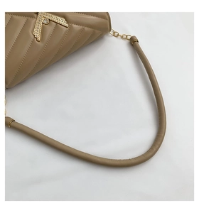 Detailed close-up of khaki quilted leather bag featuring a gold V-shaped crystal clasp