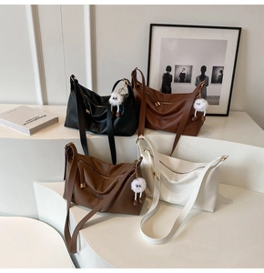 Detailed display of four textured faux leather hobo bags with cute plush charms on stand